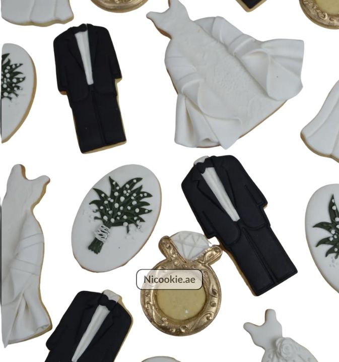 Wedding cookies shaped as white gowns and black tuxedos.