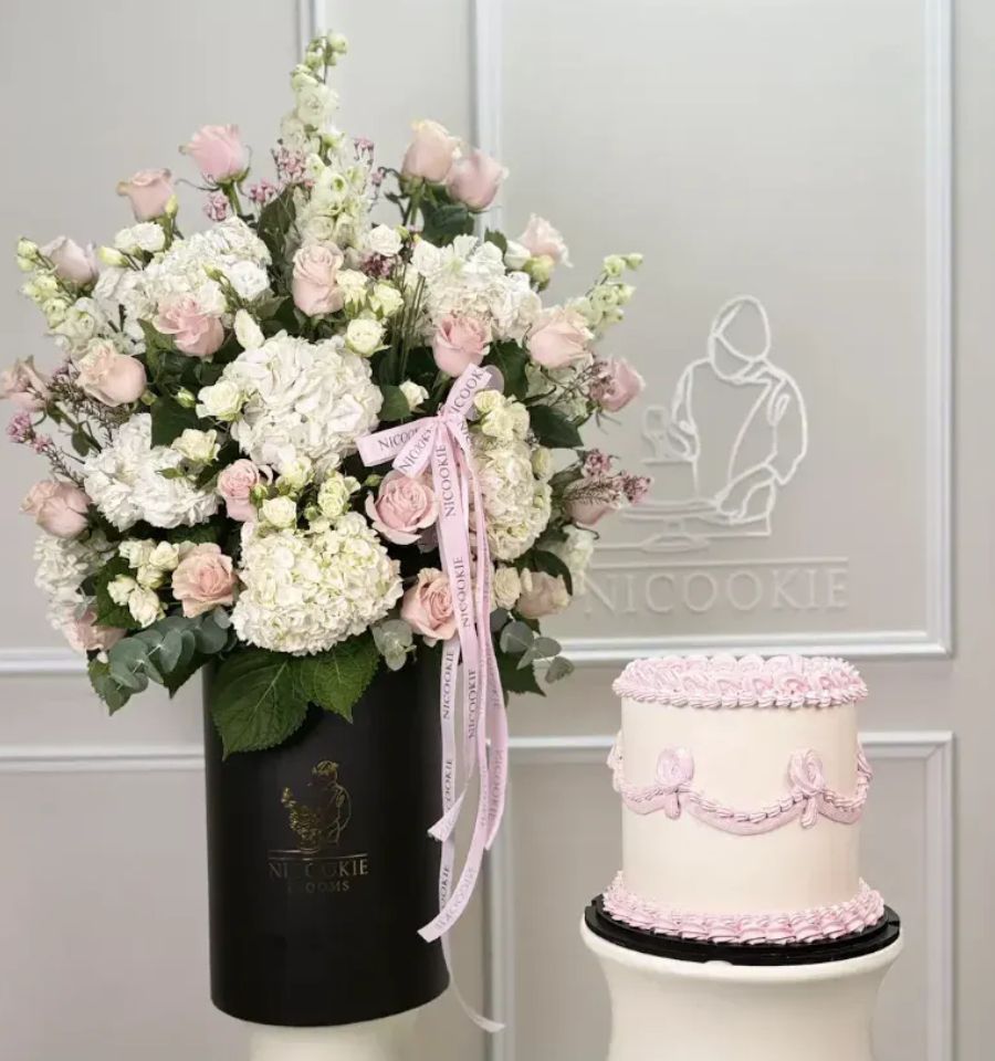 Pink roses and white hydrangeas bouquet with a pink-detailed cake.