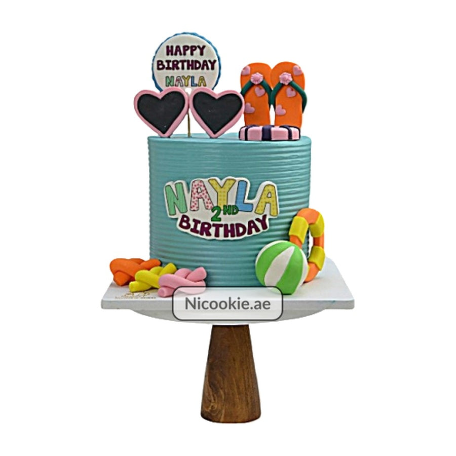 A beach-themed cake with flip-flops, hearts, and beach toys.