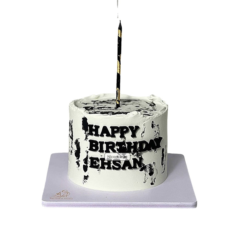A white birthday cake with black brushstrokes, "Happy Birthday Ehsan" text, and a black and gold candle.