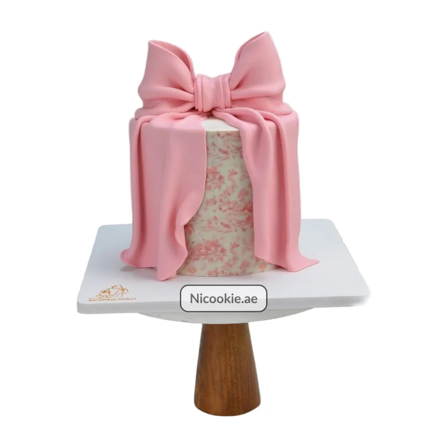 Floral bow cake with a pink fondant bow and floral pattern.