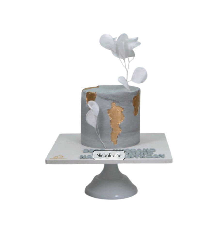 Golden marble cake with gold accents and white floral decorations.