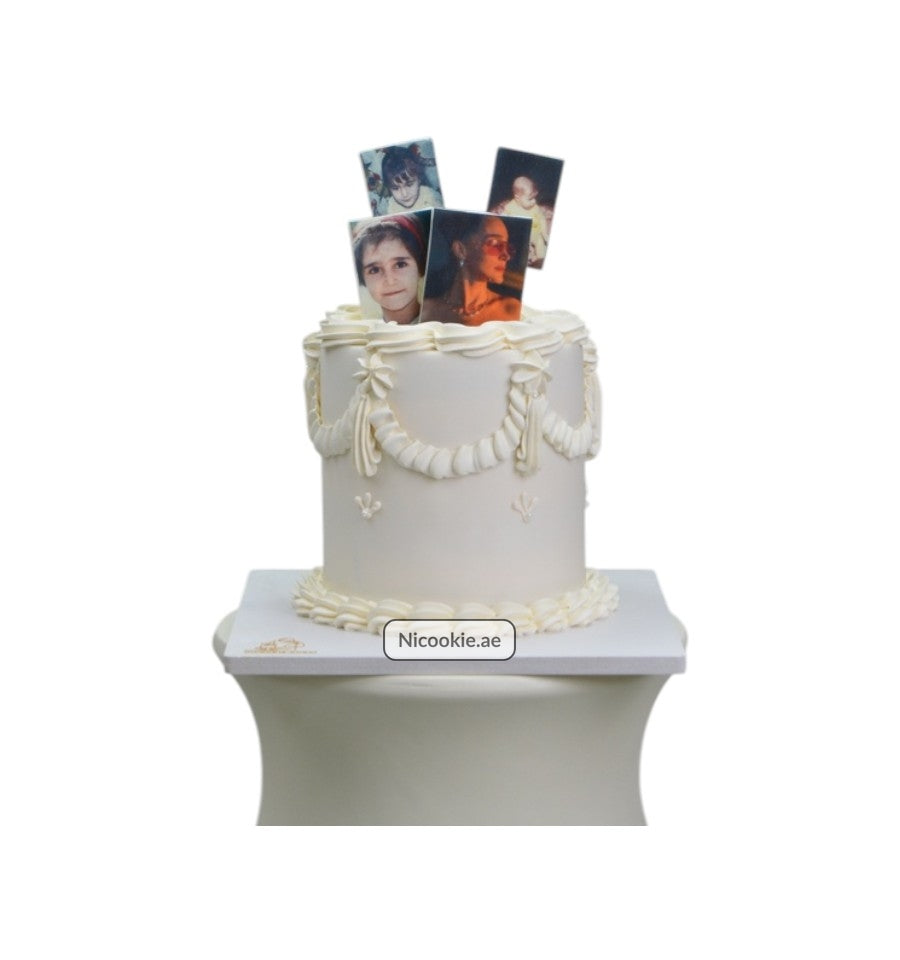 Ivory celebration cake with personal photos and white icing decorations.