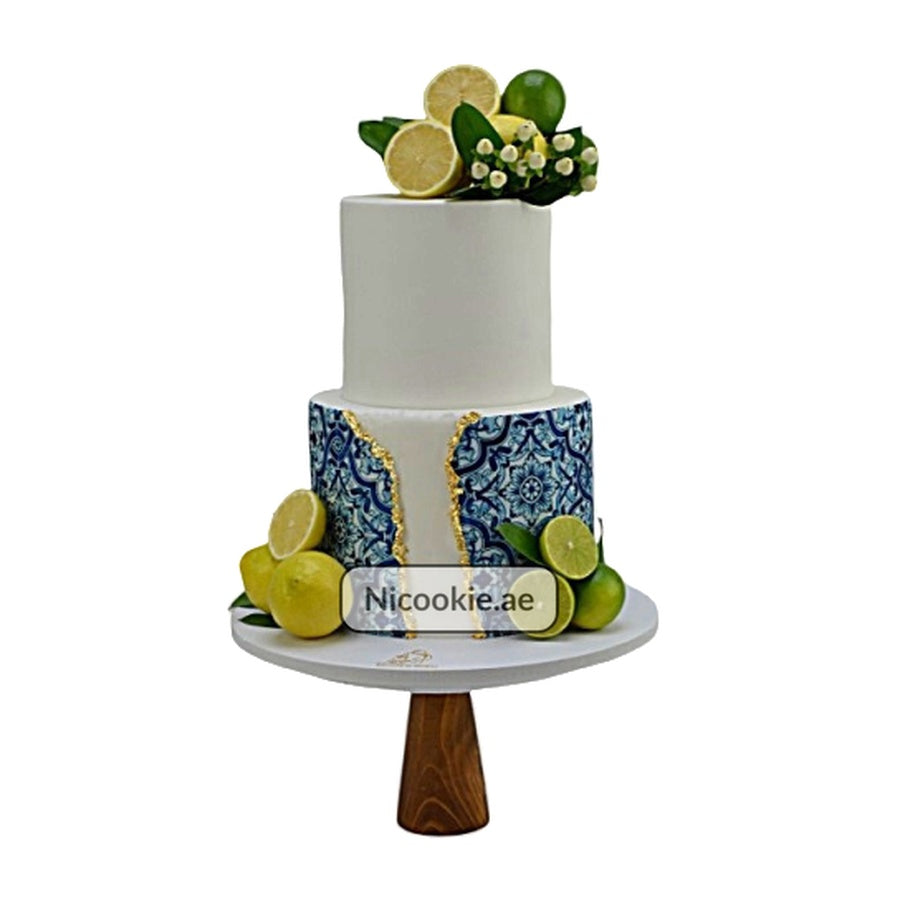Lemon and blue tile cake with gold accents and fresh citrus fruit.