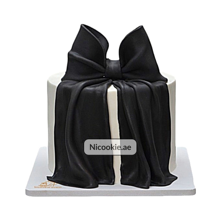 A white cake with a draped black fondant bow.