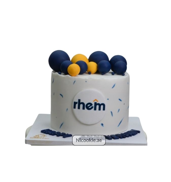 White cake with blue and yellow spheres and a "rhem" logo.