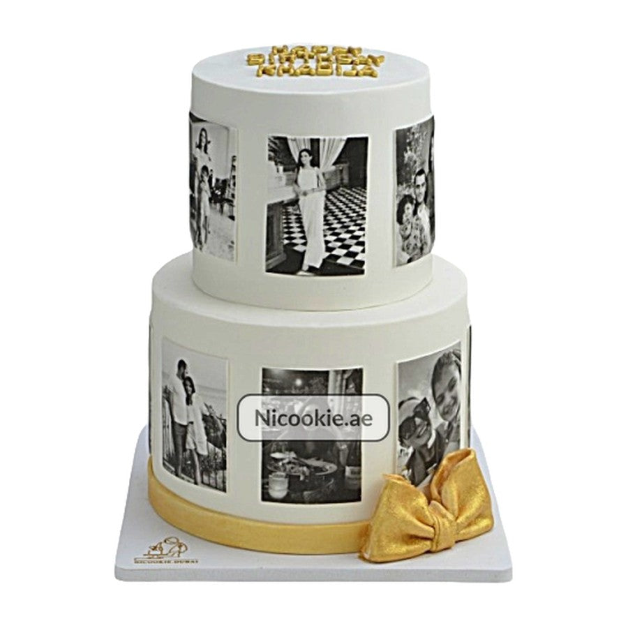 Two-tiered white cake with black and white photos and a gold bow.