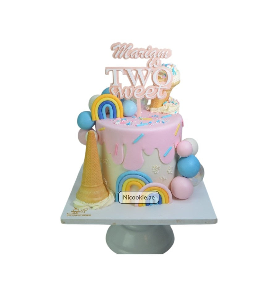 A pastel rainbow cake with ice cream and balloon decorations.