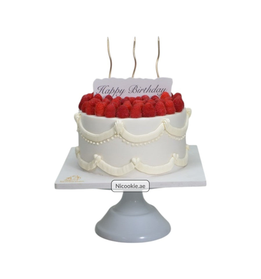 Raspberry Elegance Cake with fresh raspberries and white icing swirls.