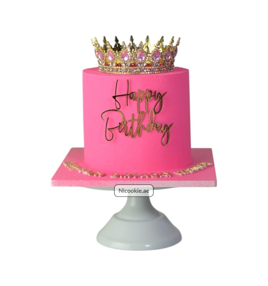 A pink cake with a gold crown and "Happy Birthday" text.