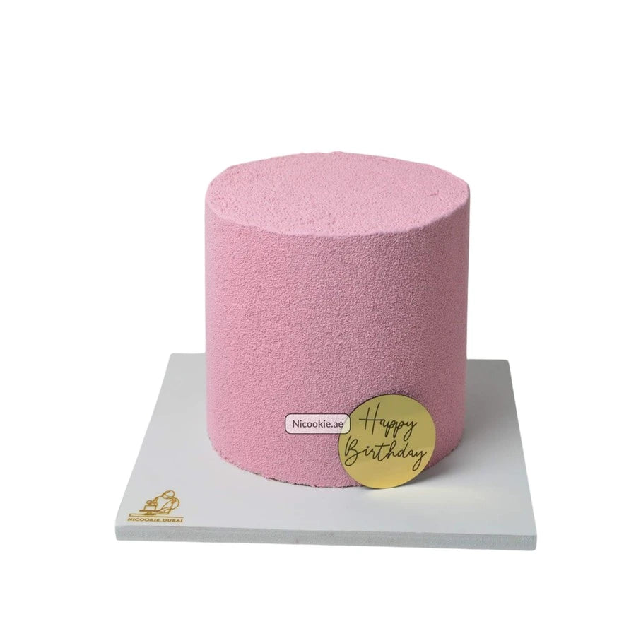 A pink velvet cake with a gold "Happy Birthday" plaque.