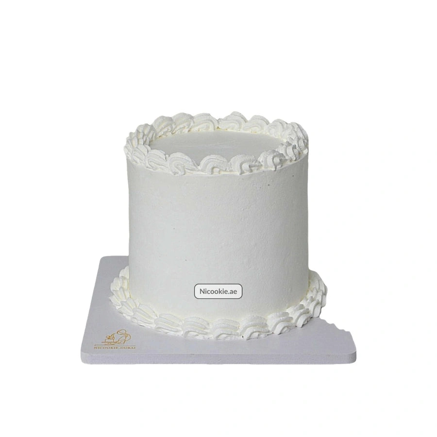 A simple white cake with piped icing trim on a white cake board.