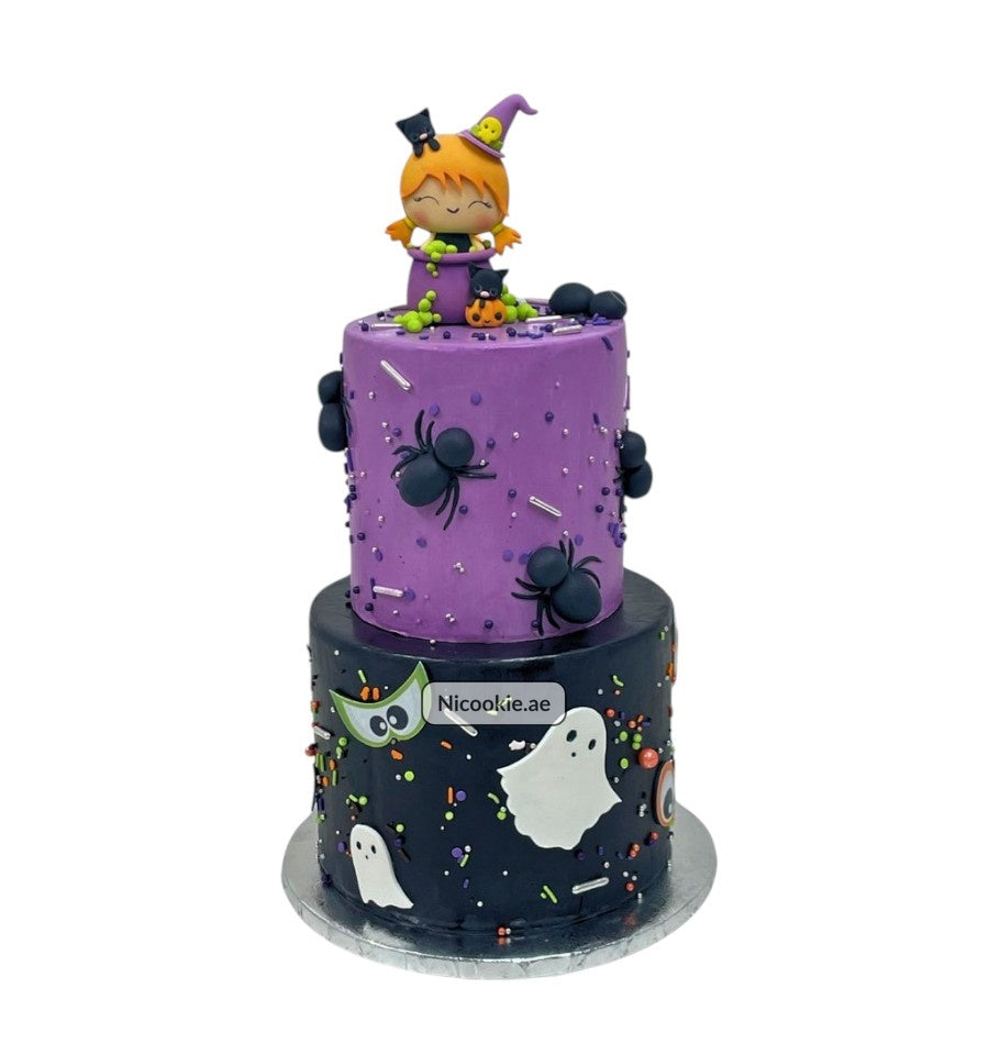 A two-tiered Halloween cake with a witch topper, spiders, and ghosts.