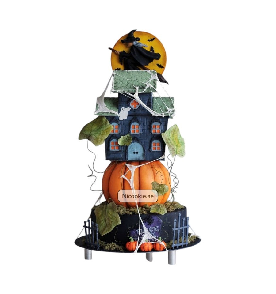 A Halloween cake featuring a witch, haunted house, and pumpkin.