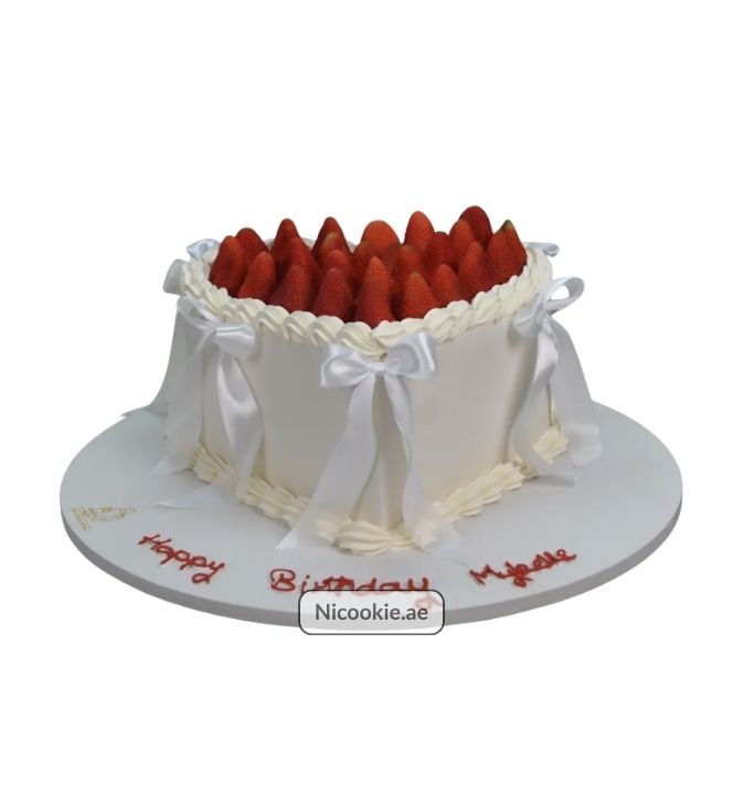 Strawberry heart cake with white ribbon bows and fresh strawberries.