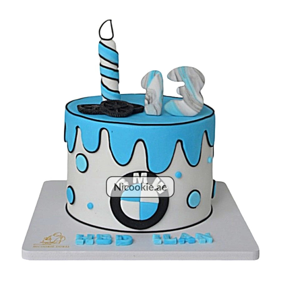 A BMW themed cake with a candle, number 13, and gears.