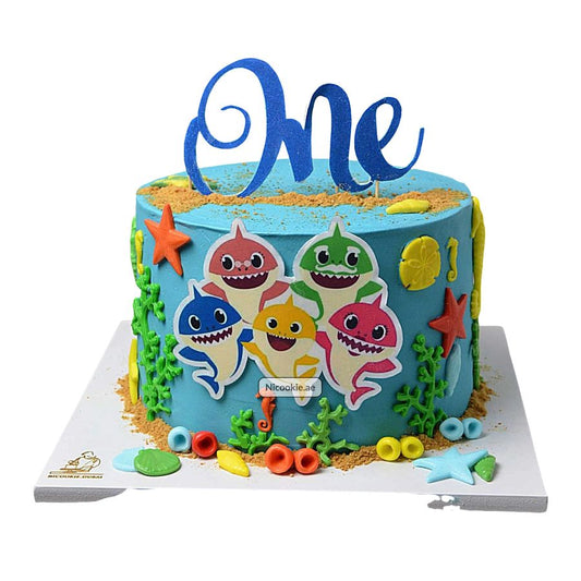 A blue Baby Shark themed cake with the word "One" on top.