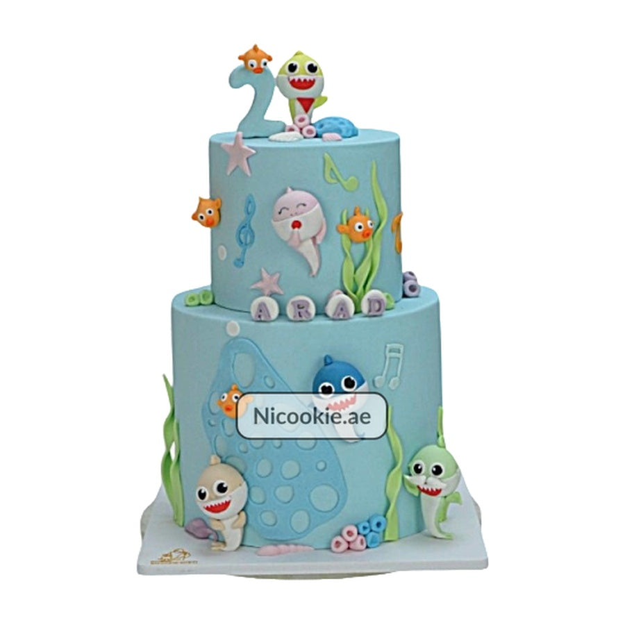 A two-tier Baby Shark cake with fondant figures and underwater decorations.