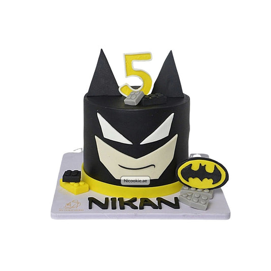 A Batman cake with a yellow number 5 and Lego-style decorations.