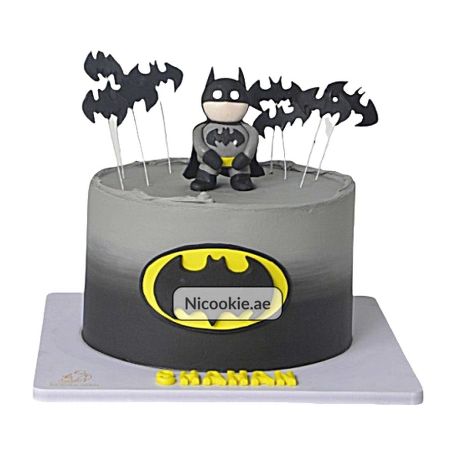 A Batman themed cake with a fondant figure, emblem, and bat silhouettes.