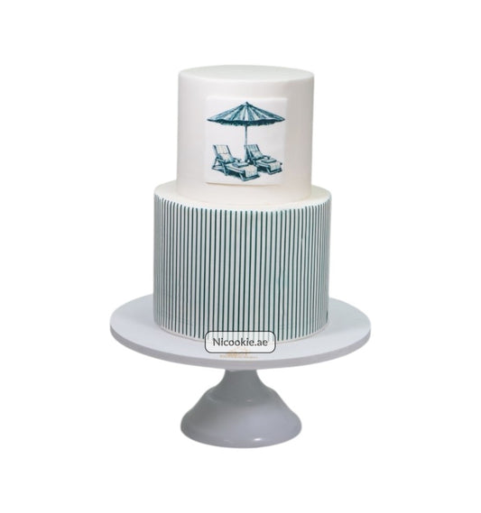 Two-tier cake with green stripes and a beach umbrella and chairs motif.