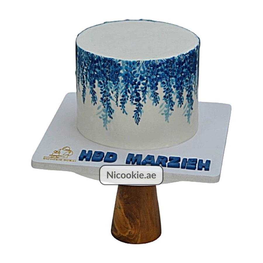 Blue floral wisteria cake on a wooden stand.