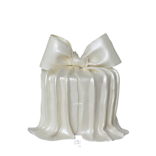 A white cake decorated to look like a gift with a large bow.