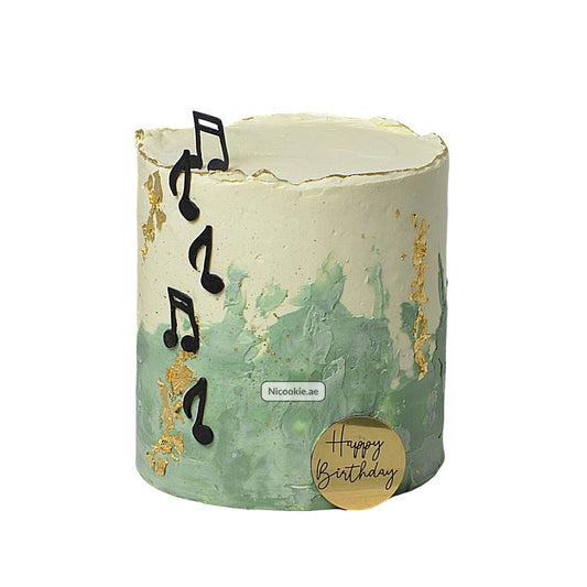 A green and white buttercream cake with musical notes and gold leaf accents.
