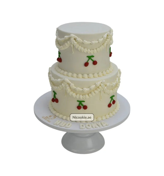Two-tier white cake with cream garlands and cherry decorations.