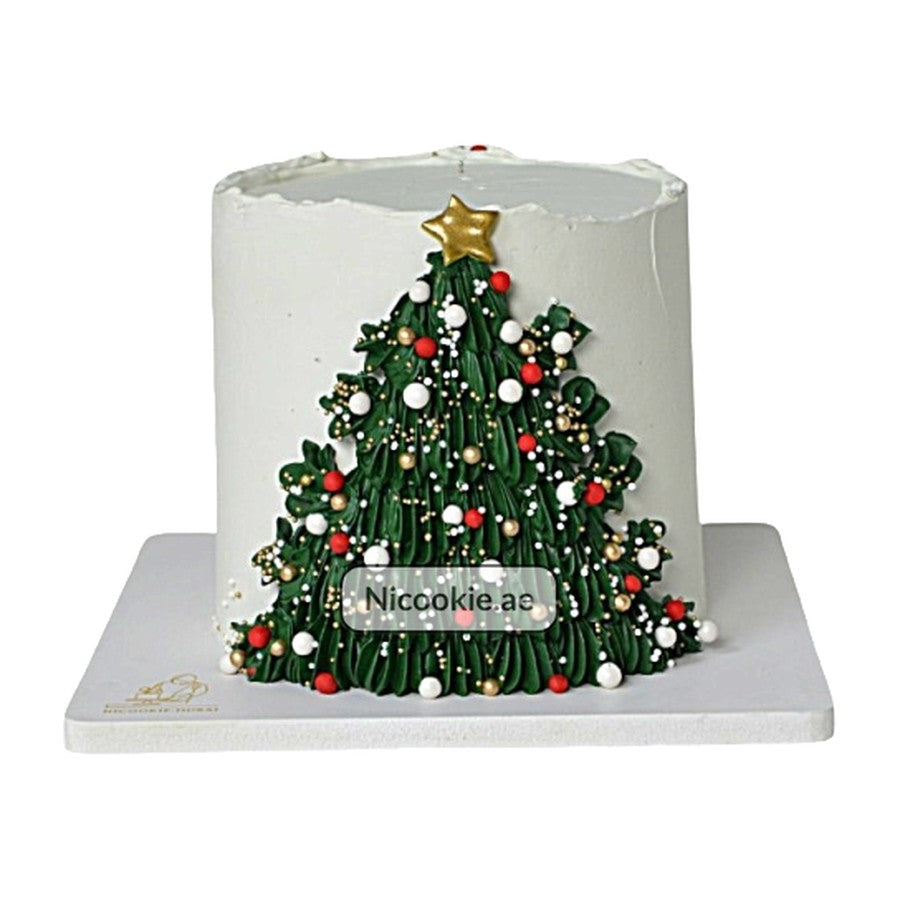 A white cake decorated with a green Christmas tree, ornaments, and a gold star.