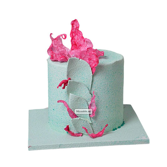Mint green cake with pink floral decorations and textured frosting.