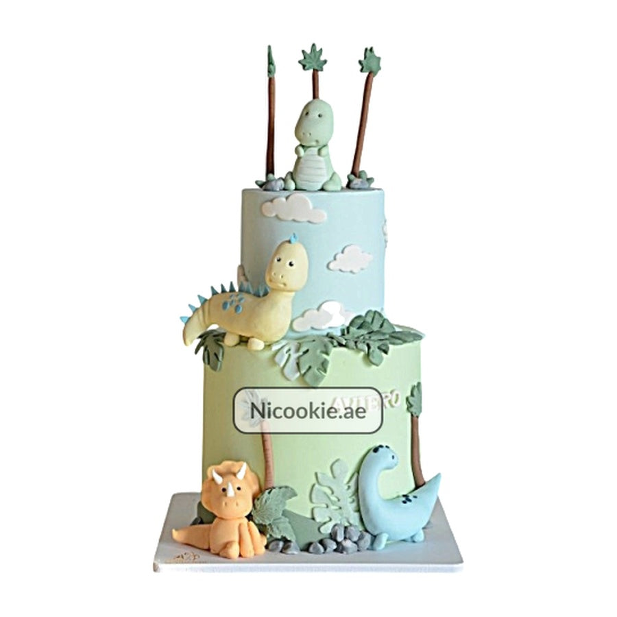 A two-tier dinosaur forest cake with fondant dinosaurs and palm trees.