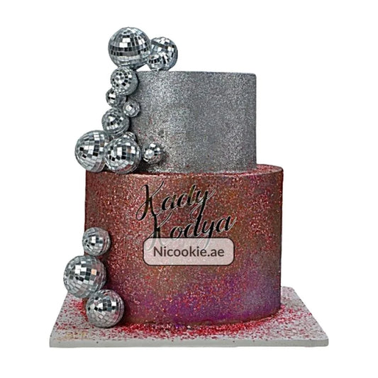 A two-tier cake decorated with silver disco balls and glitter.