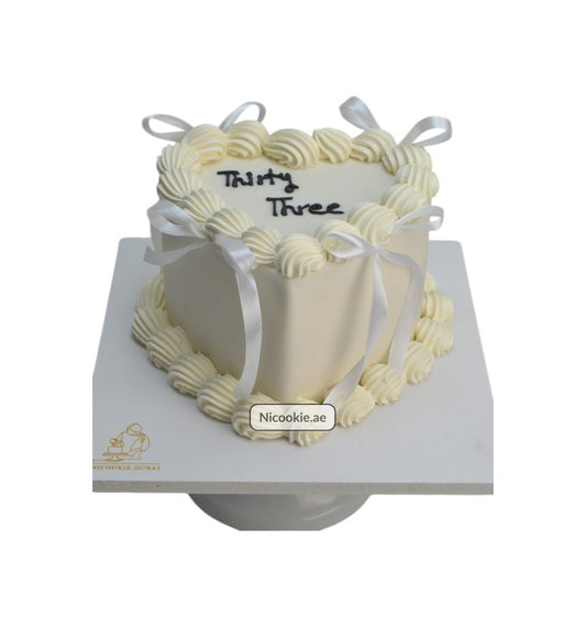 Elegant heart-shaped cake with cream swirls and ribbon details.