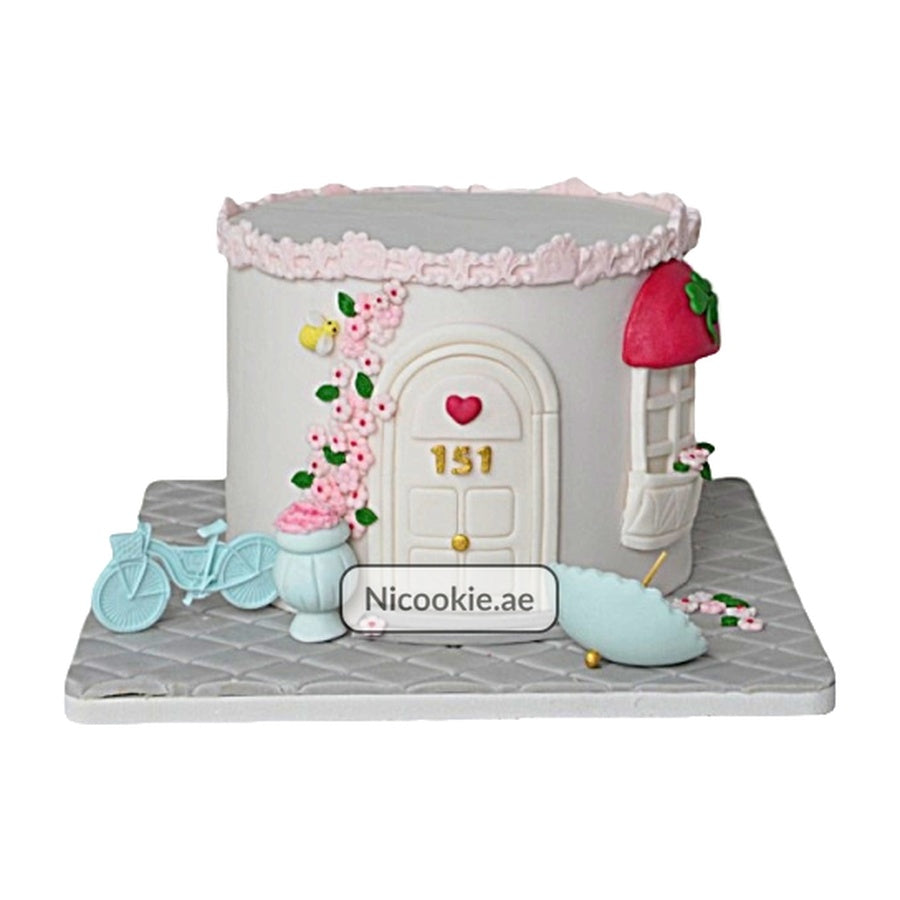 Fairy cottage cake with a strawberry roof, bicycle, and umbrella.