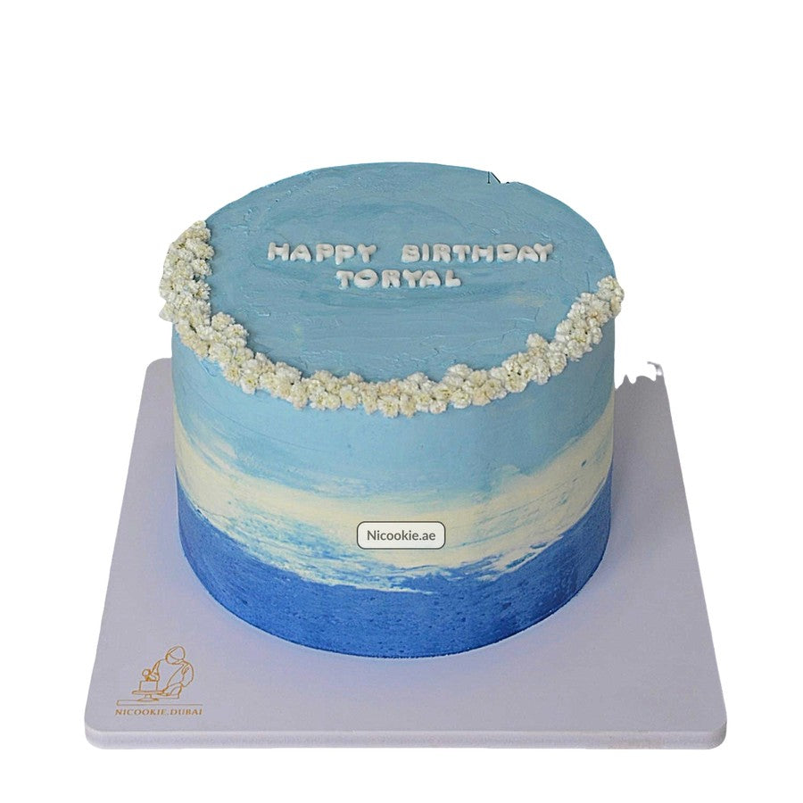 Blue ombre birthday cake with white floral accents and "Happy Birthday Toryal" text.