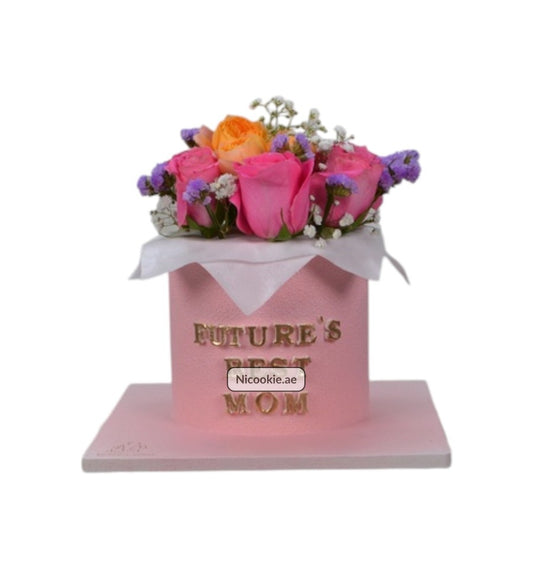 Pink cake with "Future Mom" message and floral arrangement.