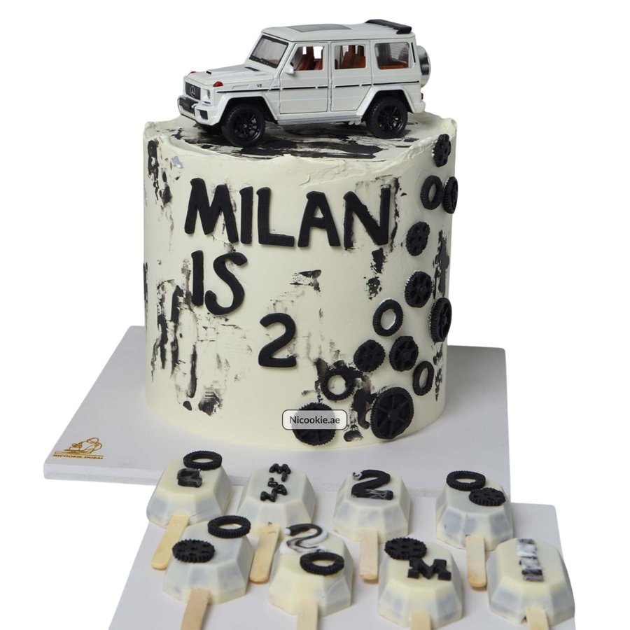 A white G-Wagon cake with black accents and a "Milan is 2" message.