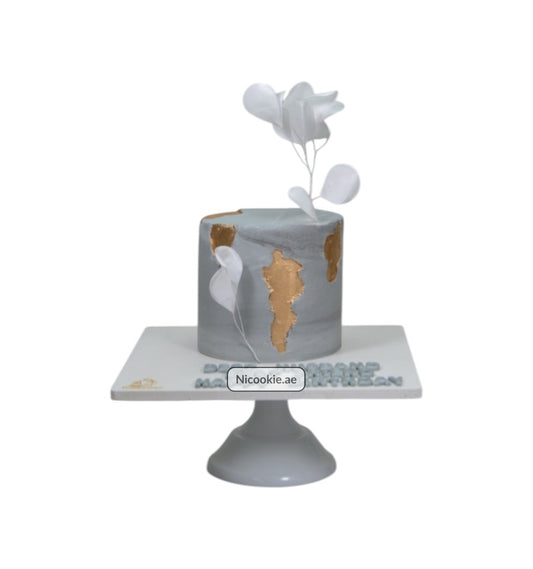 Golden marble cake with gold accents and white floral decorations.