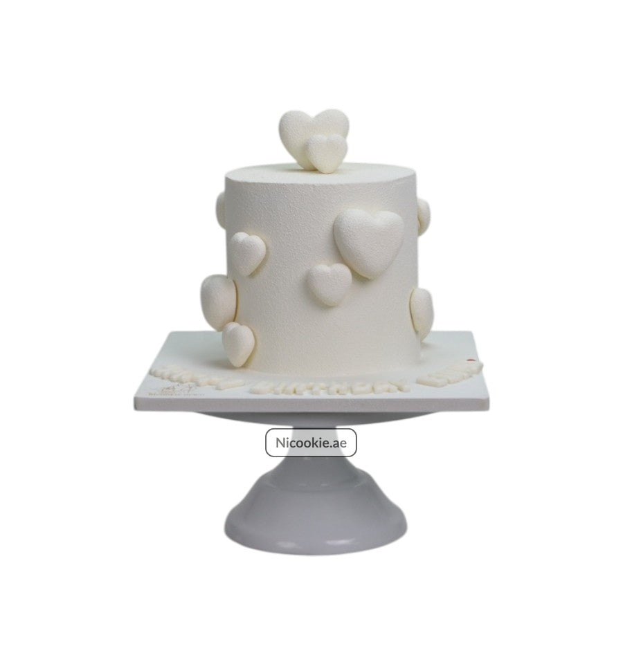 White cake with textured hearts on a cake stand.