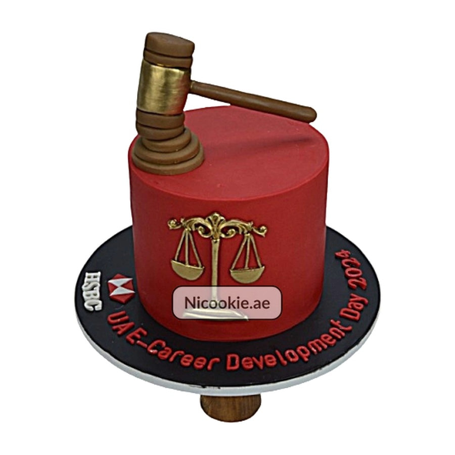 A red cake decorated with a gavel, scales of justice, and event text.