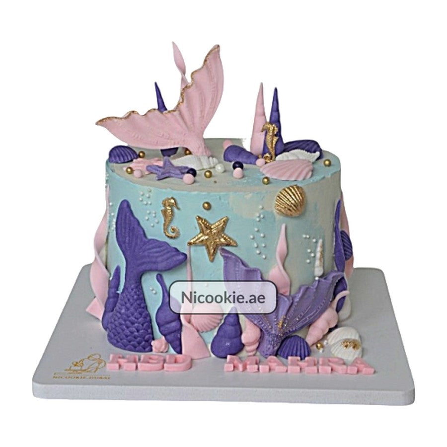 A mermaid tail fantasy cake decorated with pastel mermaid tails and seashells.