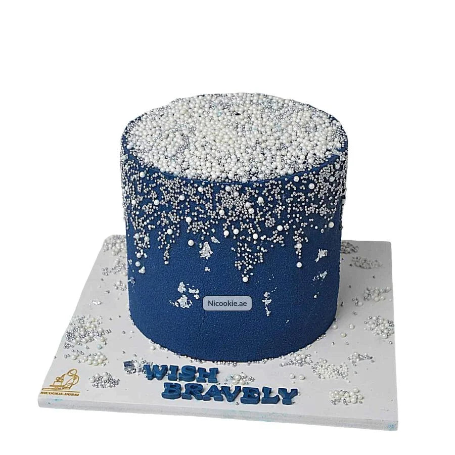 A navy blue cake covered in white and silver pearls with "Wish Bravely" written on the base.