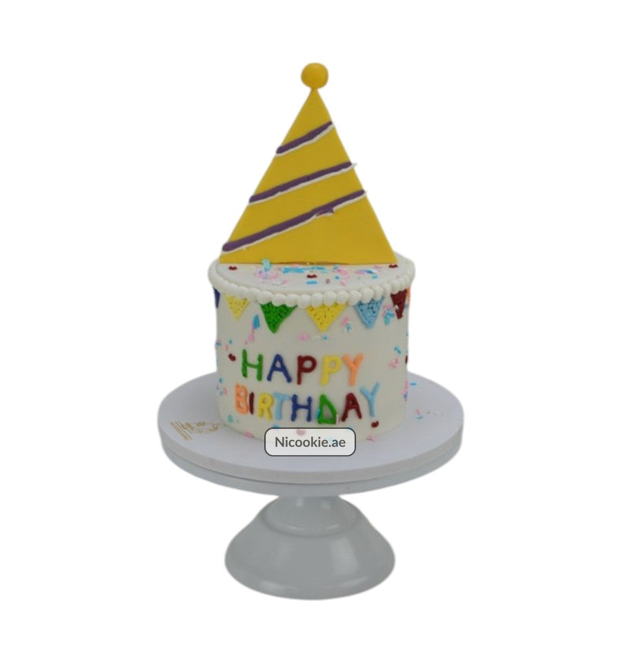 A white birthday cake with a yellow party hat and colorful "Happy Birthday" text.