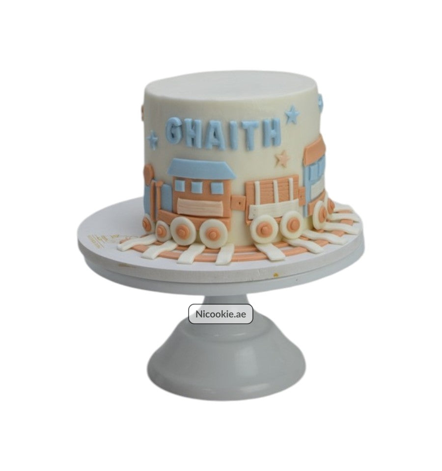 Pastel train cake with the name GHAITH decorated with train cars and stars.
