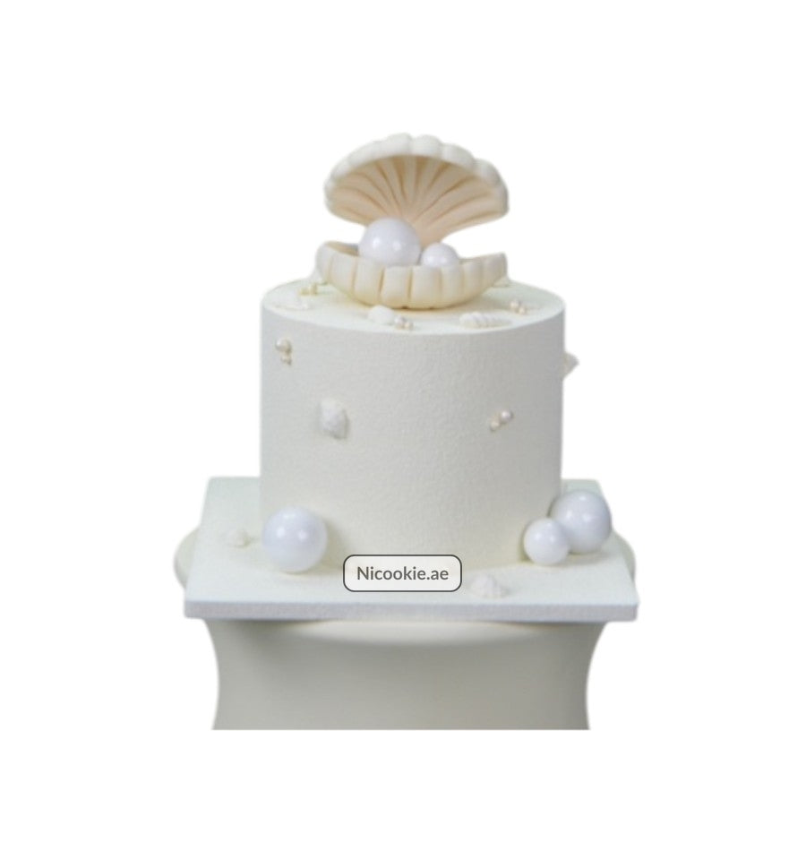 White cake with a pearl-filled shell decoration.