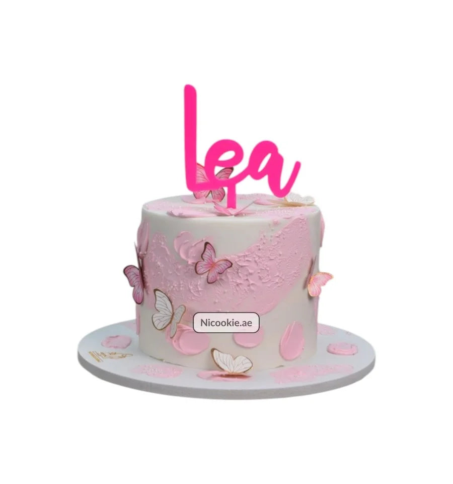 Pink cake with white frosting, pink textured frosting accents, and butterfly decorations.
