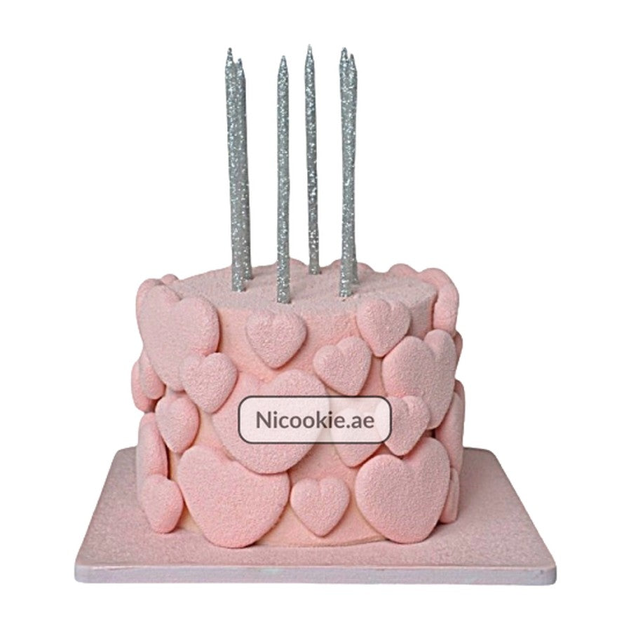 Pink cake decorated with hearts and topped with silver candles.