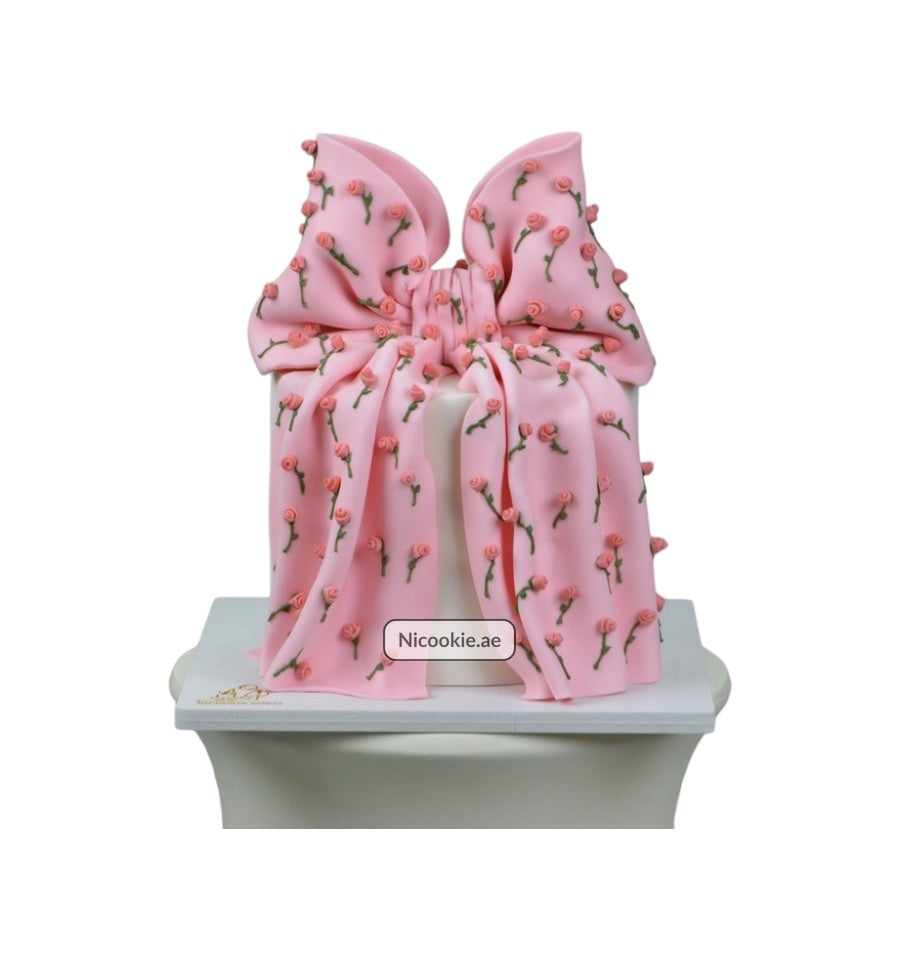 A cake decorated with a pink bow and rosebuds.