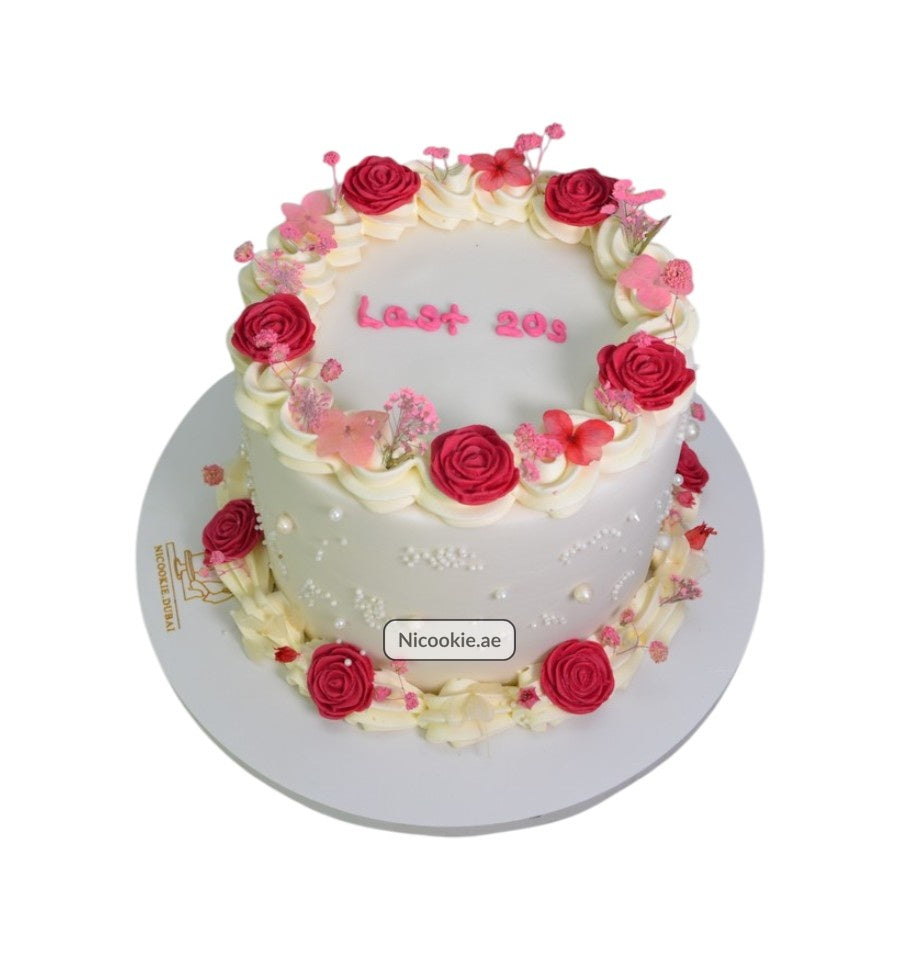 A white cake decorated with pink roses, flowers, and pearls, with "Last 20s" written on top.